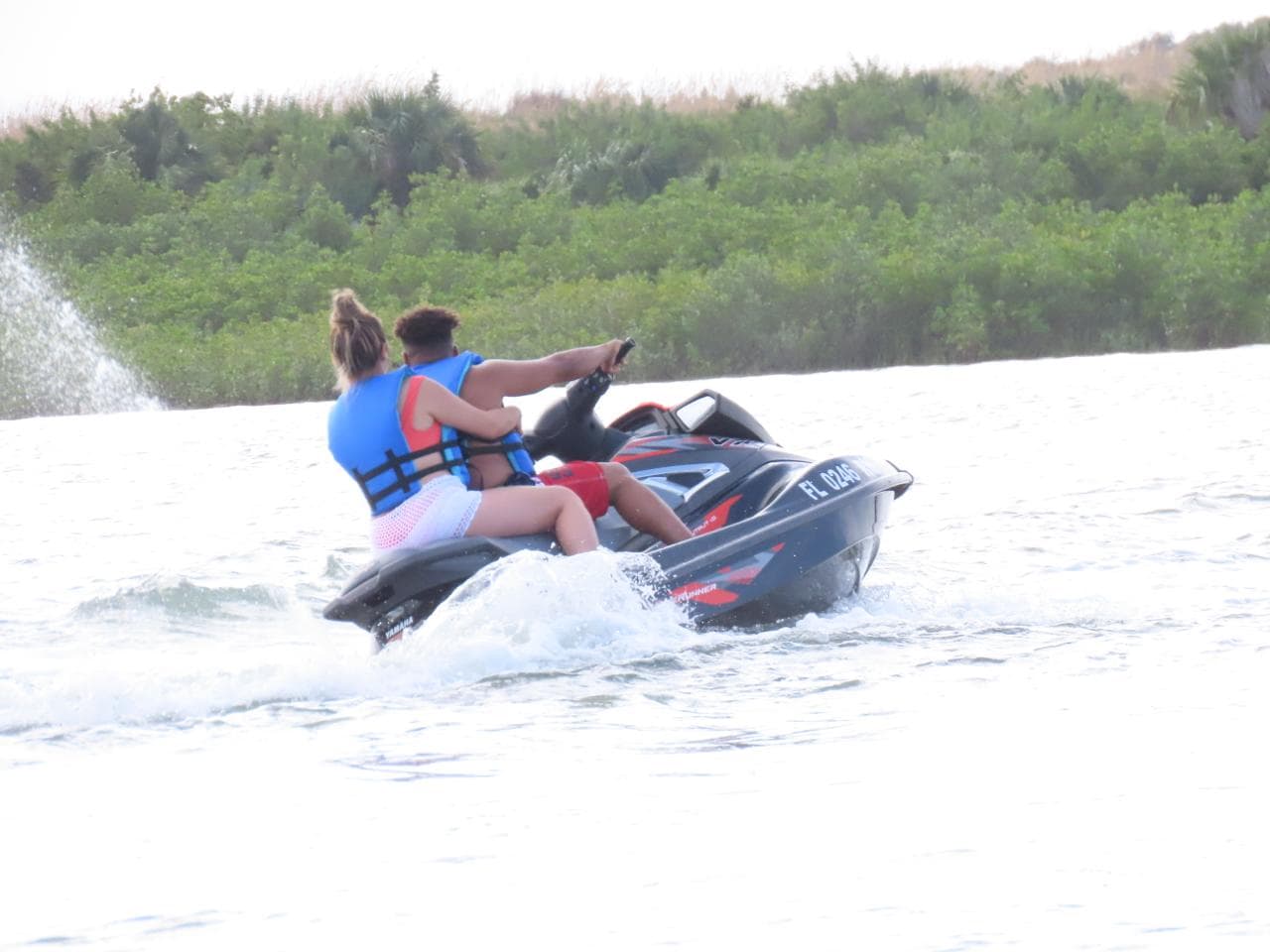 A tandem pair riding away down the estuary past the mangrove shoreline.