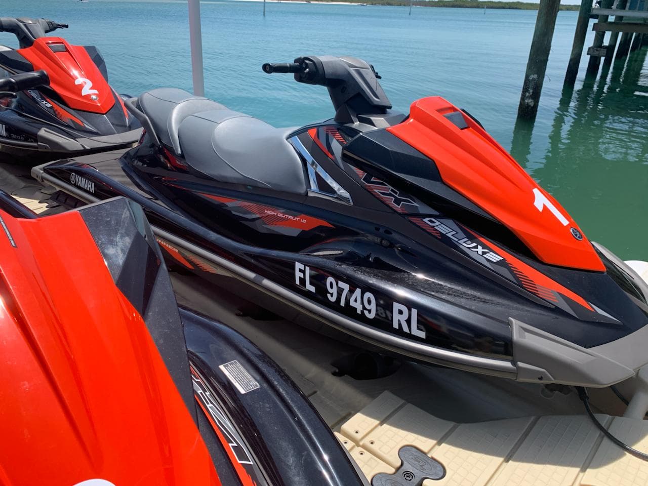 Numbered Yamaha WaveRunners tied up side by side at the dock, ready for a tour.