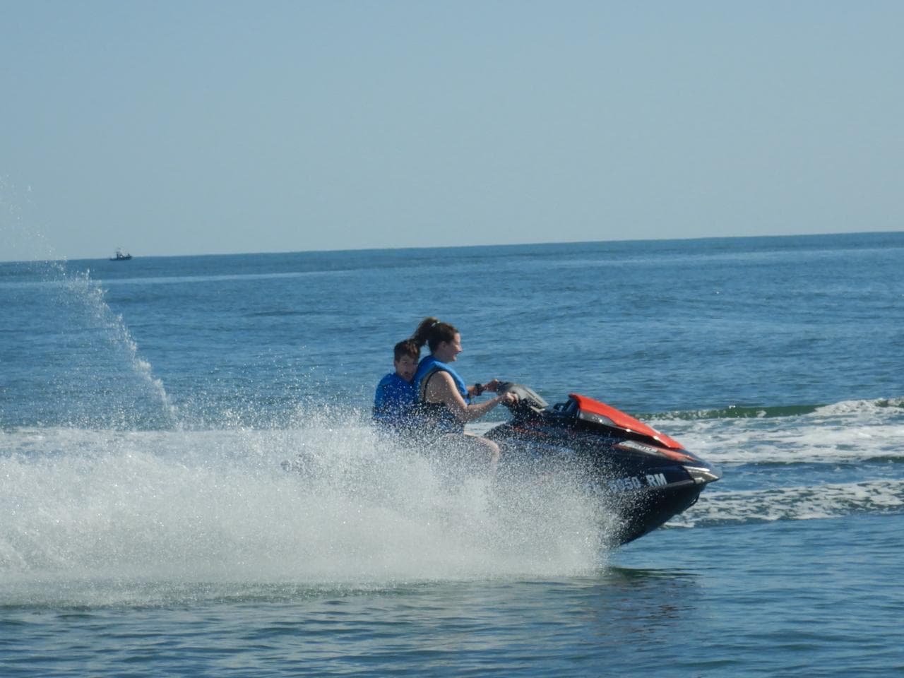 Two riders throwing a wall of spray on the open Atlantic beyond the inlet.